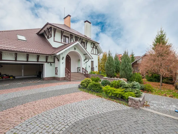 Suburban home with an interlocking brick paver driveway and walkway edged by clipped hedges